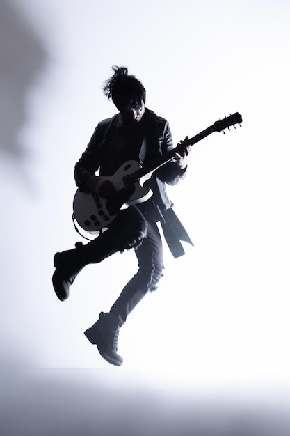 A man in a jacket is playing a guitar and is in the air.