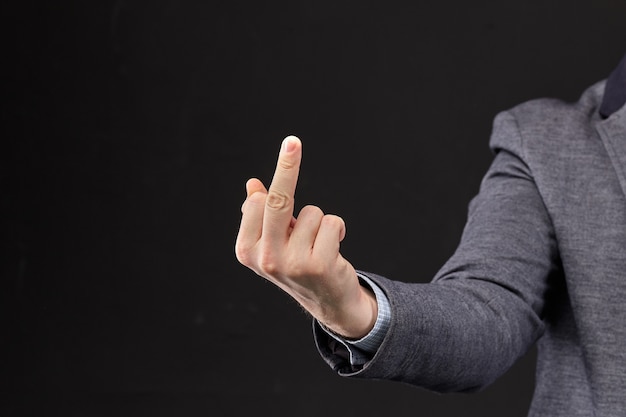 A man in a jacket shows a fuck you with his hand on a black background.