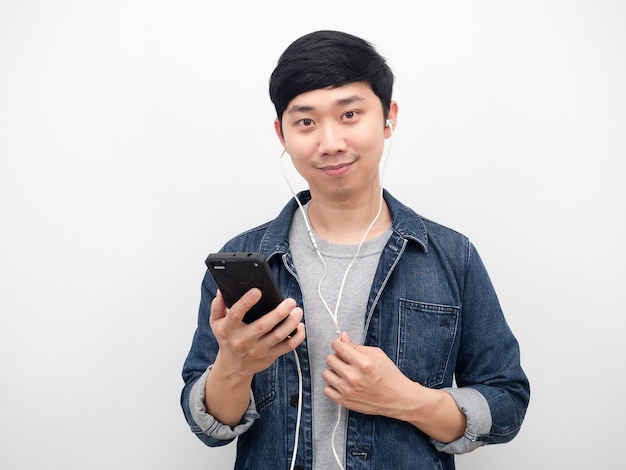 Man jeans shirt holding mobile phone using earphone portrait