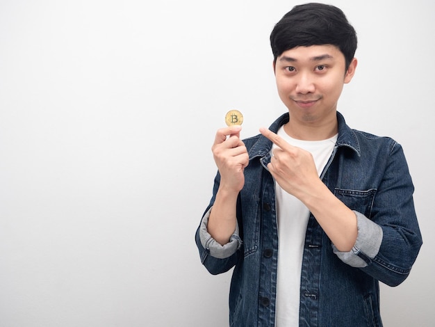 남자 청바지 셔츠는 손 복사 공간에 있는 황금 bitcoin에서 손가락을 가리킵니다.