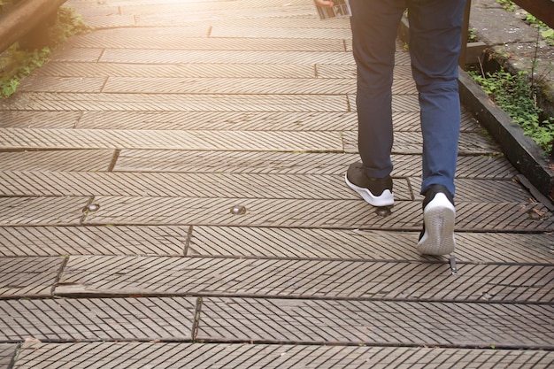 The man jeans and sneaker shoes walking on the wooden road.