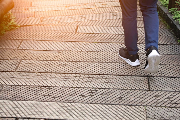 The man jeans and sneaker shoes walking on the wooden road.