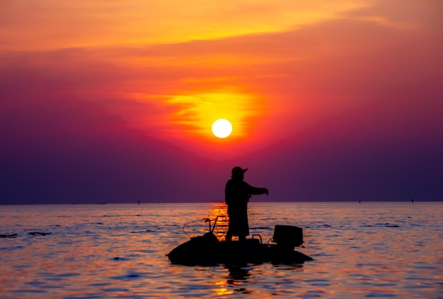 海に沈む夕日に対してジェットスキーの男