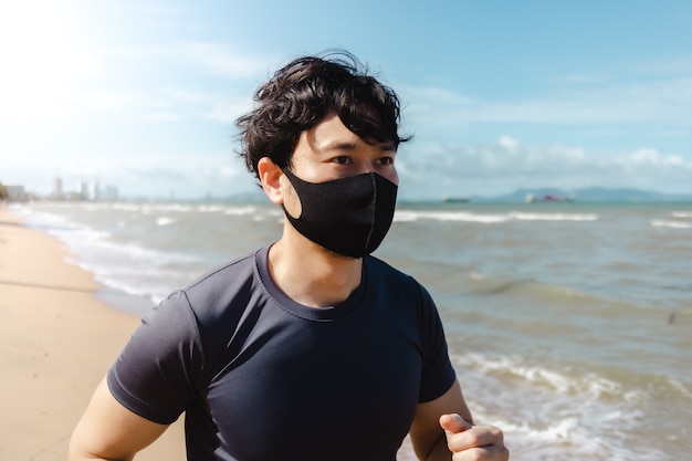 Man joggen op het strand met masker in de zomerochtend