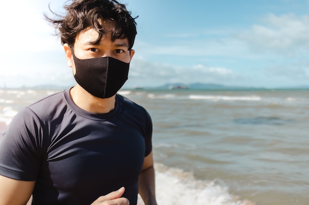 Man joggen op het strand met masker in de zomerochtend