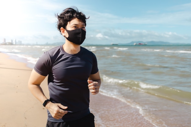 夏の朝にマスクでビーチでジョギング男