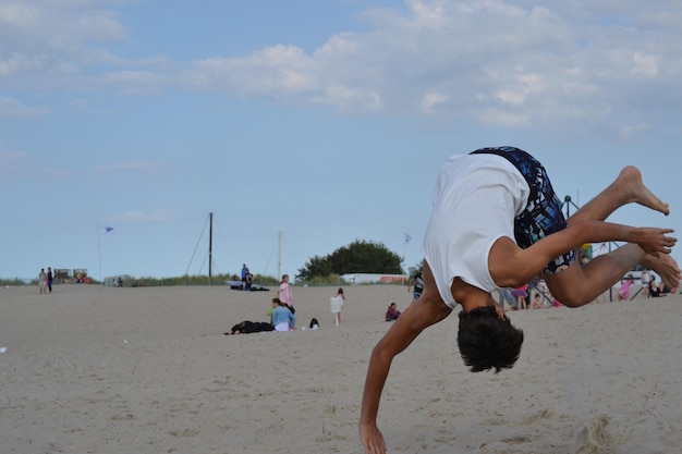 Foto uomo che salta sulla spiaggia