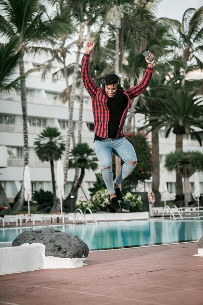 Photo man jumping by swimming pool