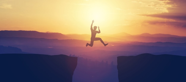 Man jumping above the cliff in the mountains.