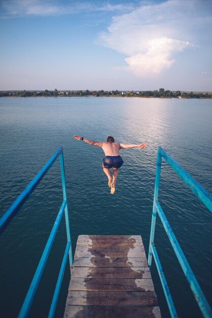 일몰에 호수 물에서 타워에서 점프하는 남자