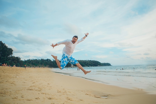 Man jumping happy in the beach with a blue sky and sea