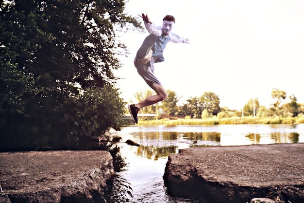 Man jumping in lake against sky