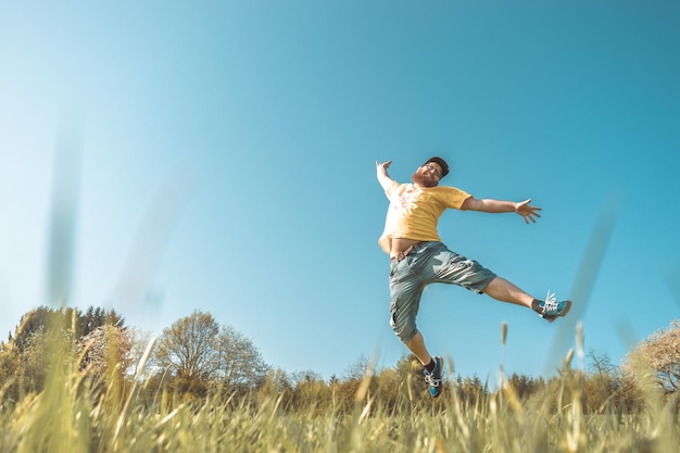 写真 明るい空の前でフィールドにジャンプする男