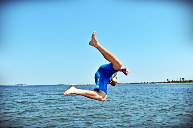 Man jumping in sea against clear sky