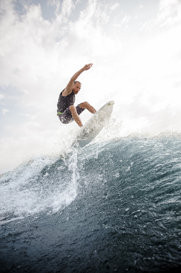 Photo man jumping on the white wakeboard down the blue water against grey sky