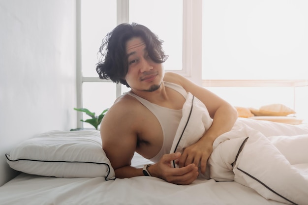 Man just wake up in a happy morning in bright white bedroom