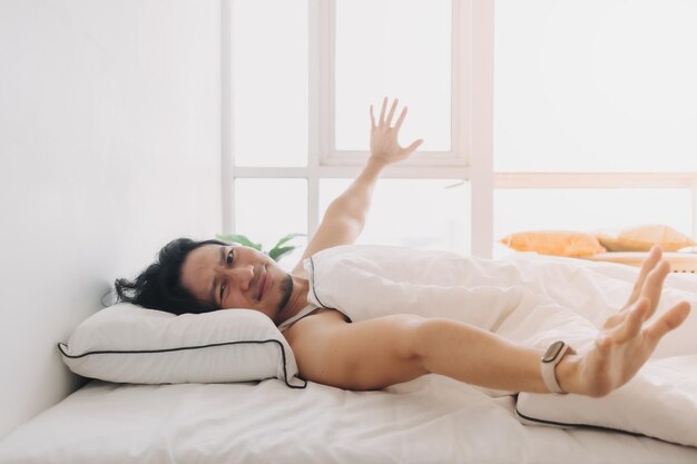 Man just wake up in a happy morning in bright white bedroom