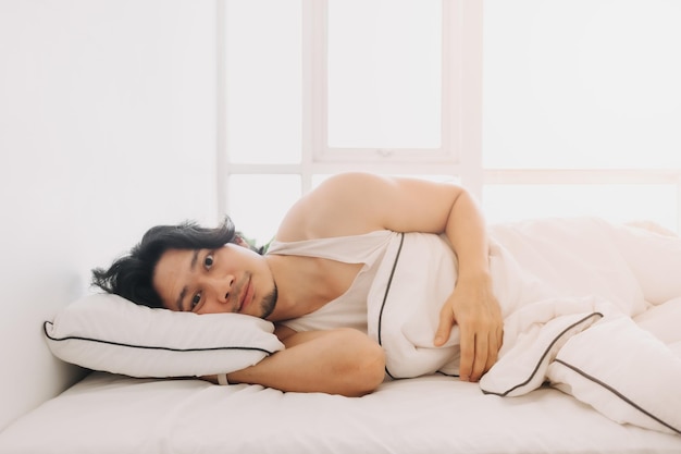 Man just wake up in a happy morning in bright white bedroom