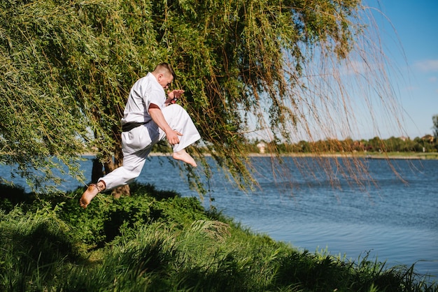 공원에서 야외 훈련 흰색 기모노를 입은 남자 가라테 파이터