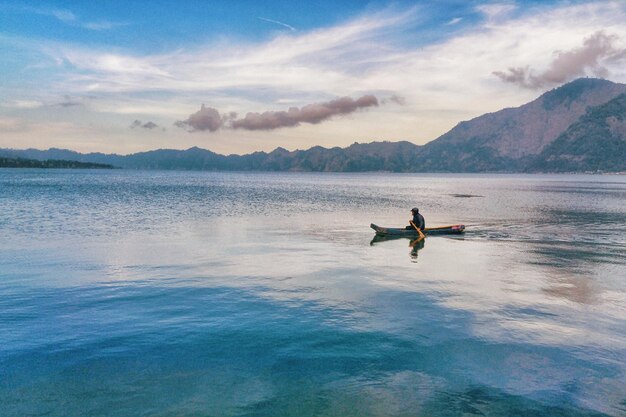 写真 空に照らして湖でカヤックを漕ぐ男