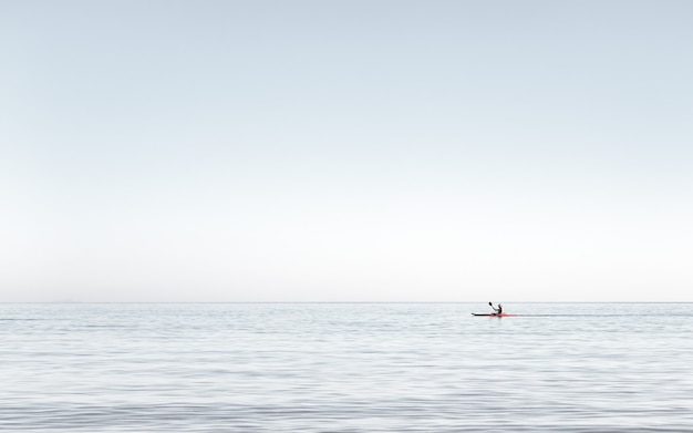 写真 海の非常に穏やかな水でカヤックをする男性エーゲ海で午後の早い時間にカヤックをする男性