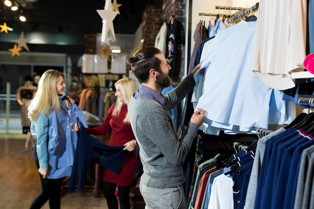 Man kiest een shirt in de winkel. verkoop, winkelen, mode, stijl en mensen concept