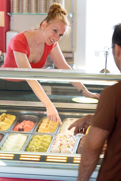 Man kiest een smaak ijs in een winkel met een vrouwelijke assistent