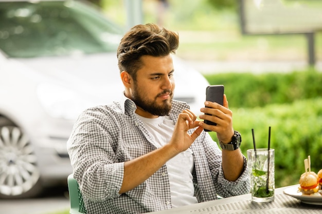Man kijken naar smartphone zittend op café terras