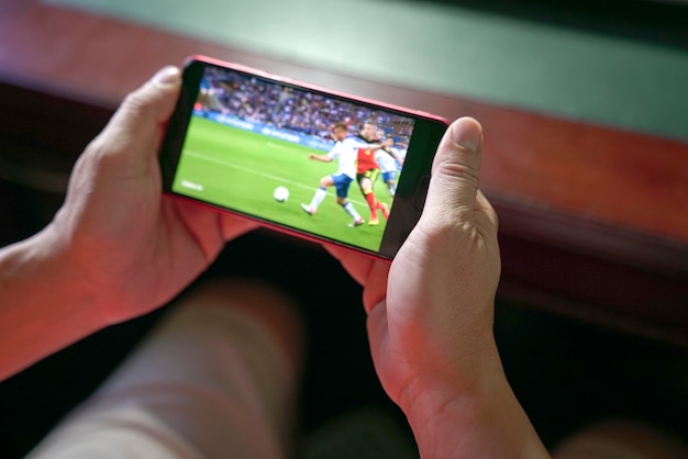 Man kijken naar voetbal en sport streamen op mobiele telefoon