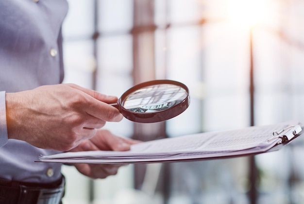 man kijkt door een vergrootglas naar documentennotitieboekje