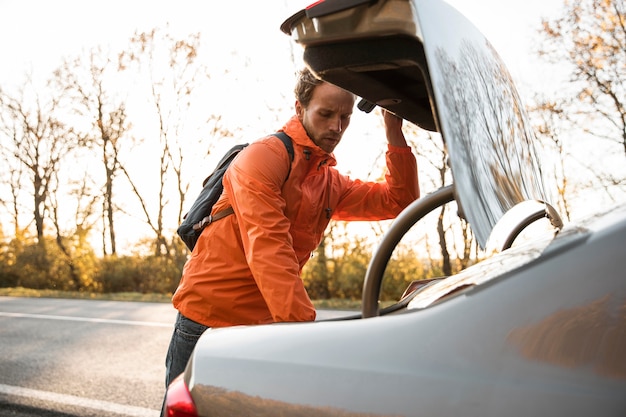 Foto man kijkt in de kofferbak van de auto tijdens een roadtrip