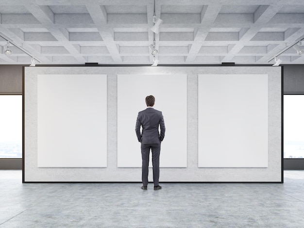 Foto man kijkt naar drie posters in een galerie