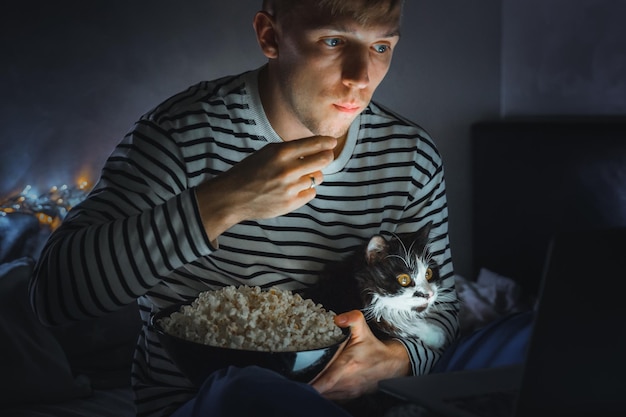 Foto man kijkt naar een film met een kat thuis.