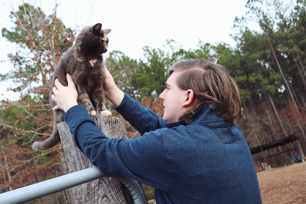 Foto man kijkt naar kat tegen bomen