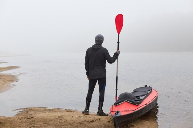 Man kijkt naar mistig water, wil roeiboot, genietend van het prachtige landschap