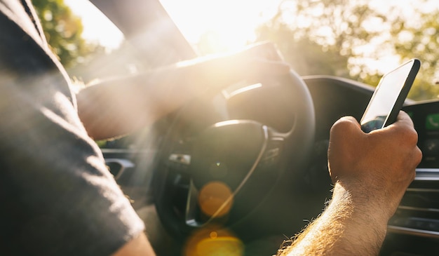 Man kijkt naar mobiele telefoon tijdens het autorijden