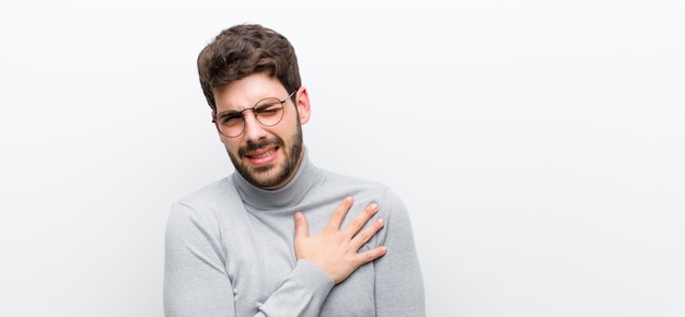 Man kijkt verdrietig, gekwetst en diepbedroefd, houdt beide handen dicht bij het hart, huilt en voelt zich depressief