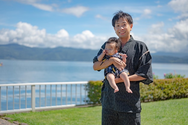 A man in a kimono holds a baby in his arms.