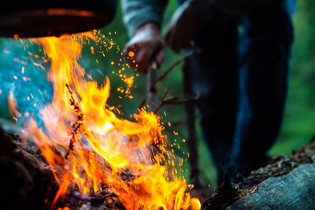 L'uomo accende il falò nella foresta. fiamma atmosferica di fuoco da vicino. campeggio sulla natura. riposo attivo ricreazione all'aria aperta. bello fuoco arancio con fumo con lo spazio della copia.