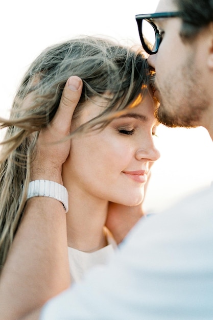 Man kisses woman on the forehead holding her head in his hands Portrait