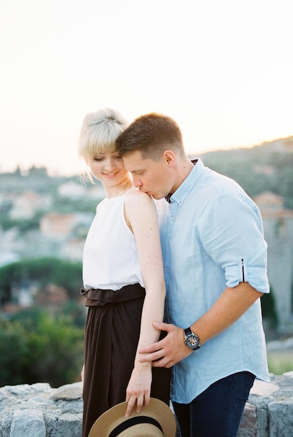 Man kisses woman on the shoulder hugging her from behind