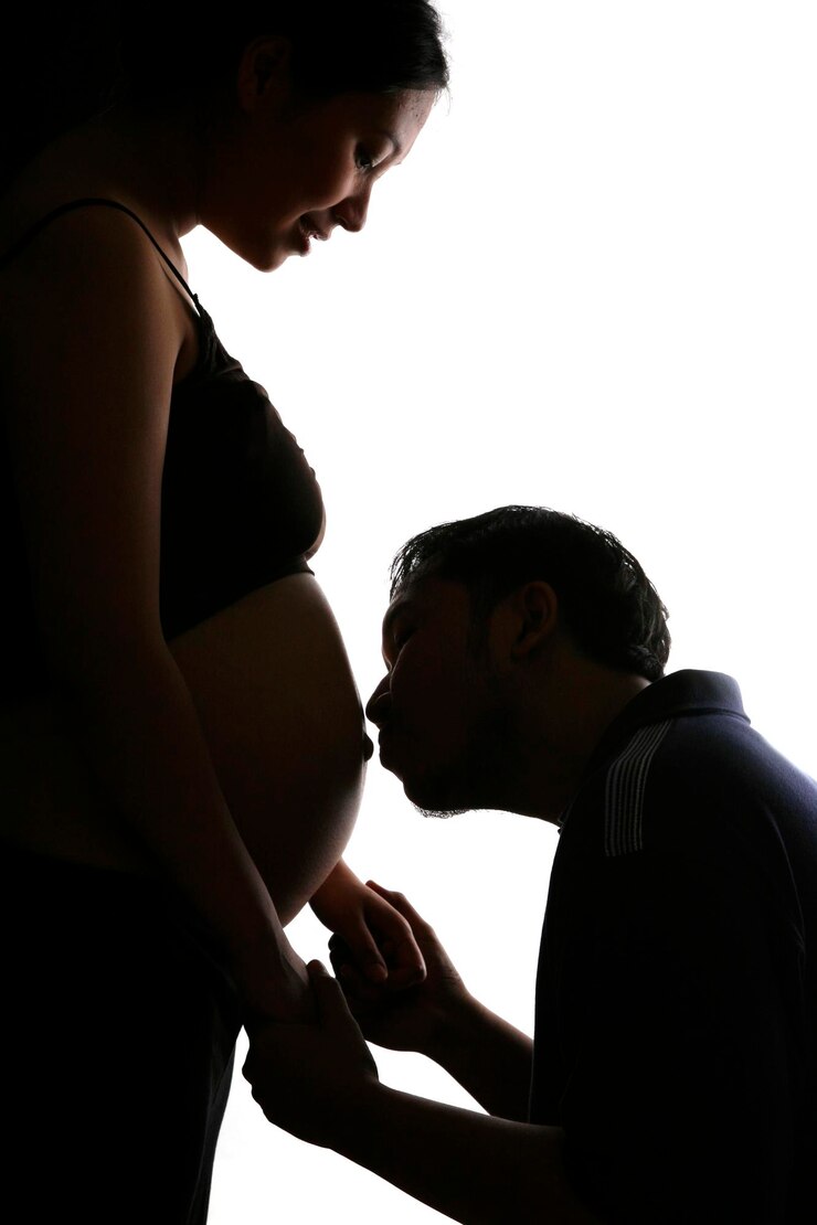 Photo 白い背景で妊娠中の女性の腹部にキスする男性