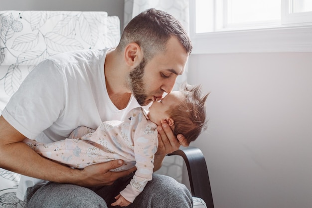 Photo man kissing daughter while sitting on armchair at home