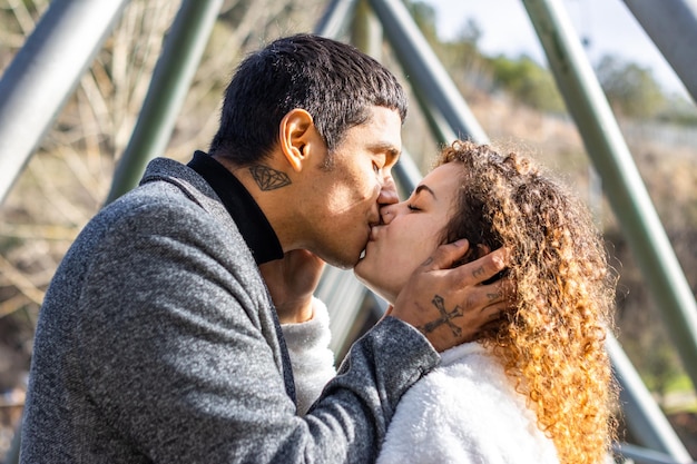 Man kissing his girlfriend outdoors Guy hugging and kissing his girlfriend