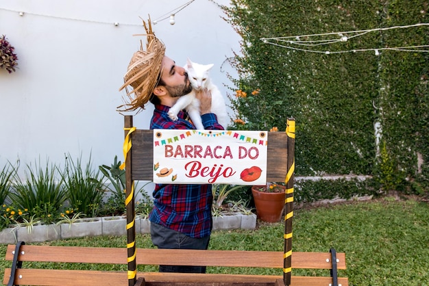 Man kissing pet cat at brazilian june party festa junina Translation kissing tent