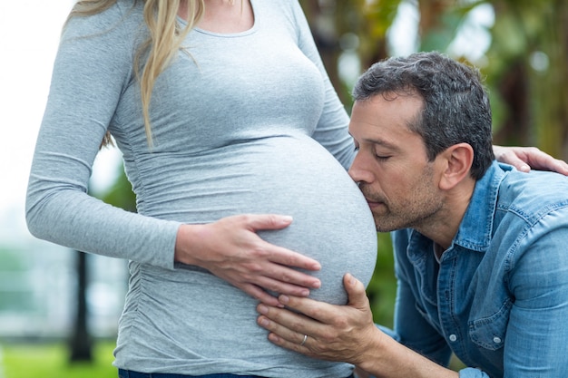 L'uomo che bacia lo stomaco della donna incinta all'aperto