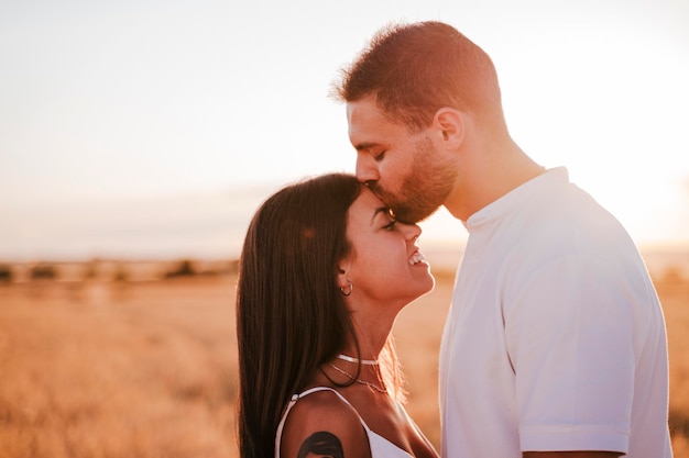 夕暮れの空に立って女性の額にキスをする男性