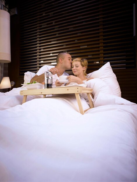 写真 ホテルの部屋のベッドで女性にキスする男性