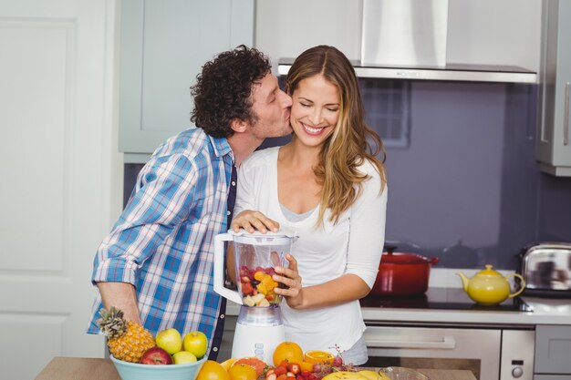 Uomo che bacia la donna che prepara un succo di frutta