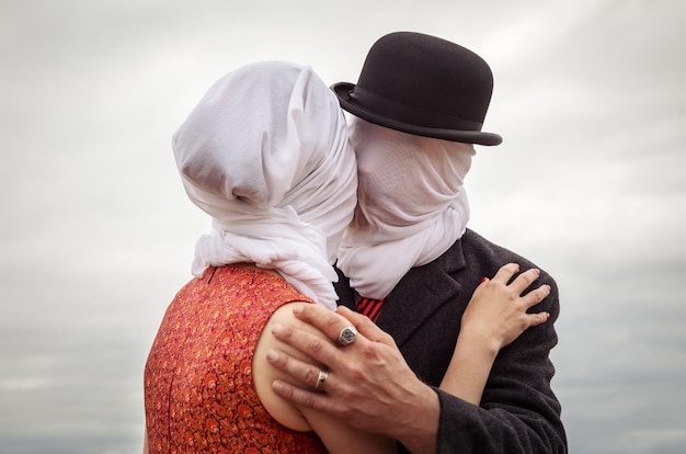 Man kissing woman with white fabrics on their heads